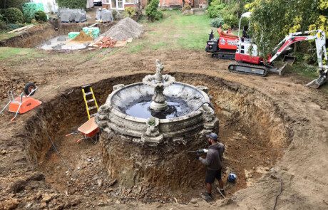 Garden landscaping team installing large water fountain feature.