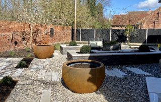 Early stages of raised borders having newly added plants, bulbs and flowers. Border designed and landscaped by the Essex Garden Co.
