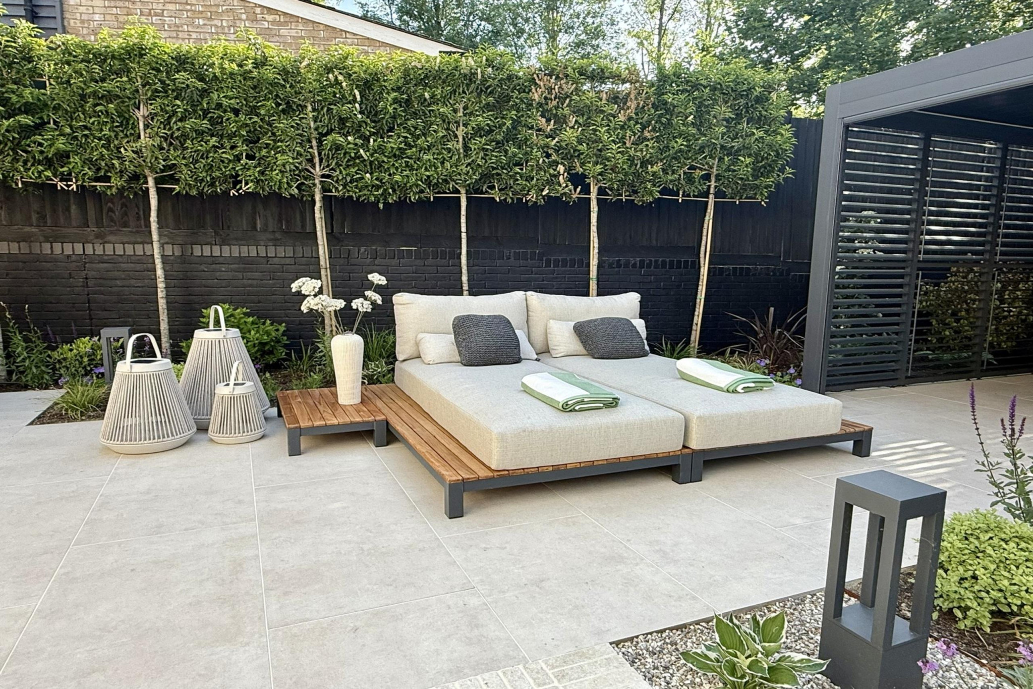 Full garden re-design in Warley, Essex.Low maintenance garden design. Porcelain paving in pergola entertainment area with sun loungers.