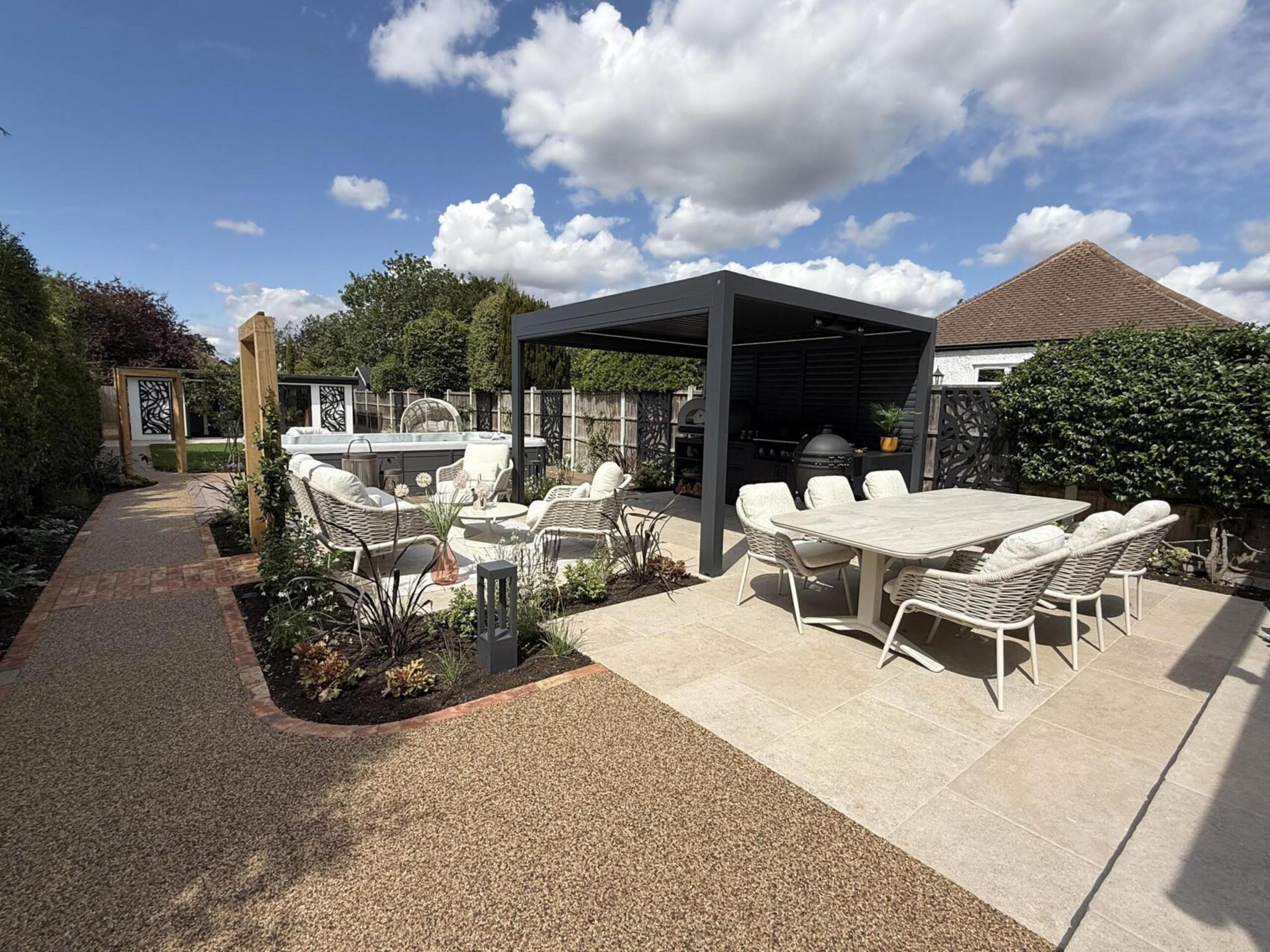 Garden transformation in Corbetts Avenue, Upminster. Essex. Features include: porcelain paving, clay pavers, louvered pergola, outdoor kitchen, swim spa, rain arch, lighting, planting, turf, resin, Irrigation. Garden design and lanscape transformation by The Essex Garden Co.