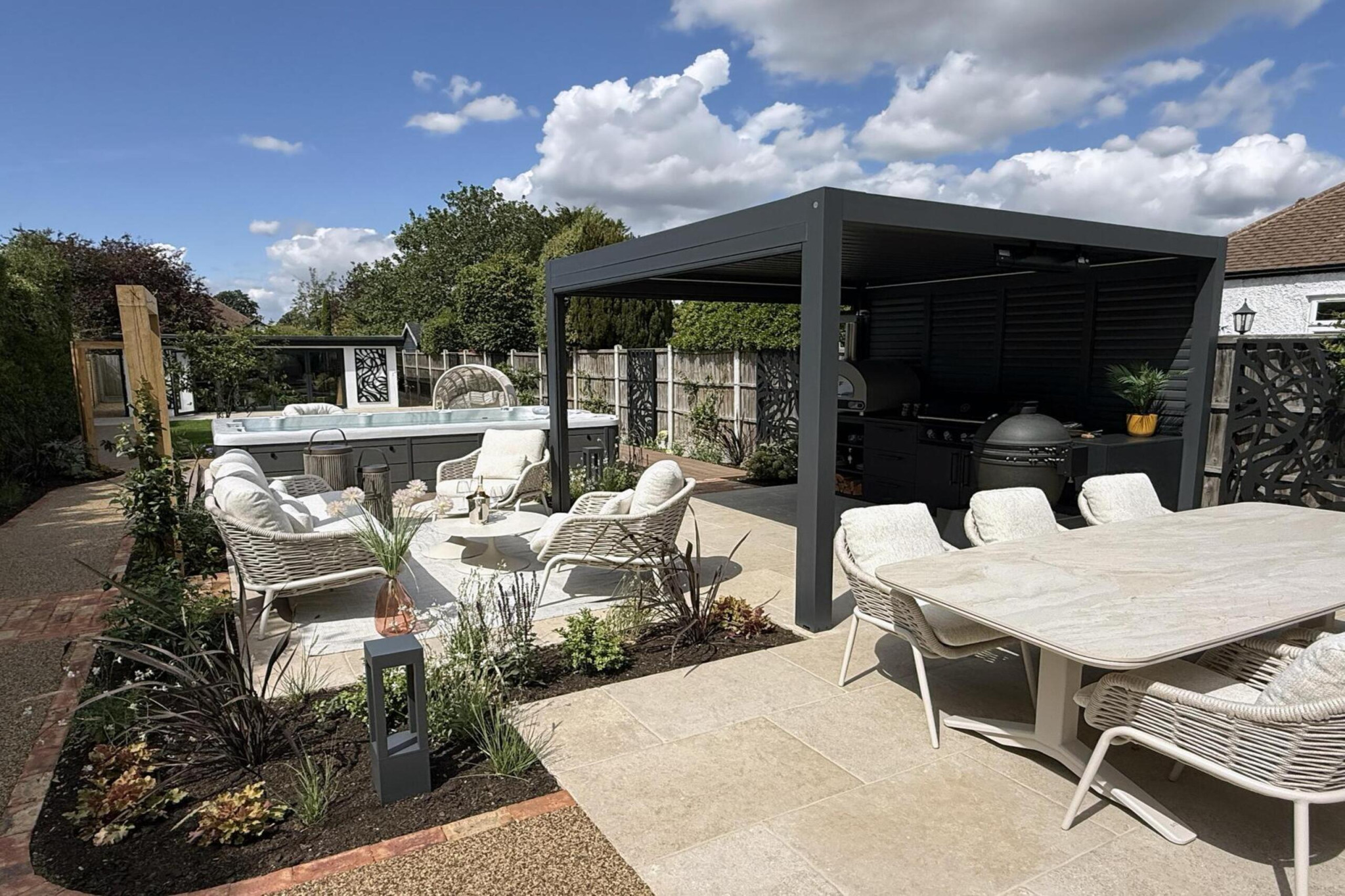 Garden transformation in Corbetts Avenue, Upminster. Essex. Features include: porcelain paving, clay pavers, louvered pergola, outdoor kitchen, swim spa, rain arch, lighting, planting, turf, resin, Irrigation. Garden design and lanscape transformation by The Essex Garden Co.