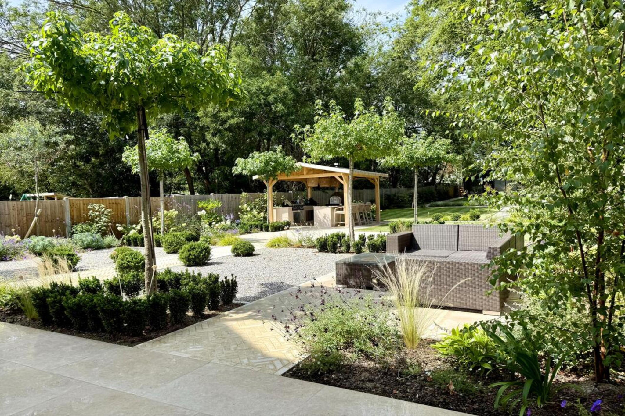 Garden project in Hall Lane, Upminster. Essex Garden design showing landscaping features: porcelain paving, feature pavers, timber gazebo, outdoor kitchen, umbrella trees, lighting, planting, turf, stabilising grids, gravel and irrigation.