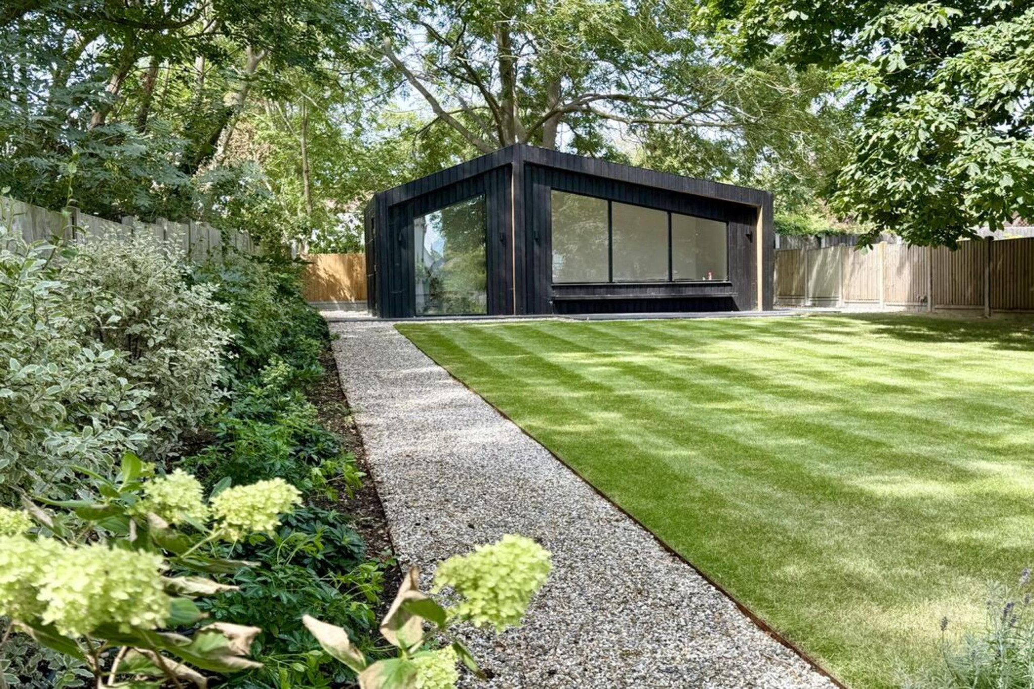 Garden transformation in Hall Lane, Upminster. Essex garden design and landscaping features: porcelain paving, feature pavers, timber gazebo, outdoor kitchen, umbrella trees, lighting, planting, turf, stabilising grids, gravel and irrigation.